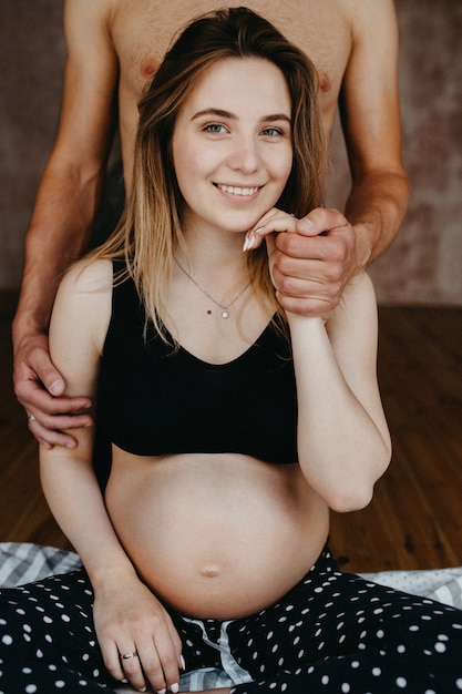 Concept De Grossesse, De Repos, De Personnes Et D'attente - Heureuse Femme Enceinte Assise Sur Le Lit Et Toucher Son Ventre à La Maison