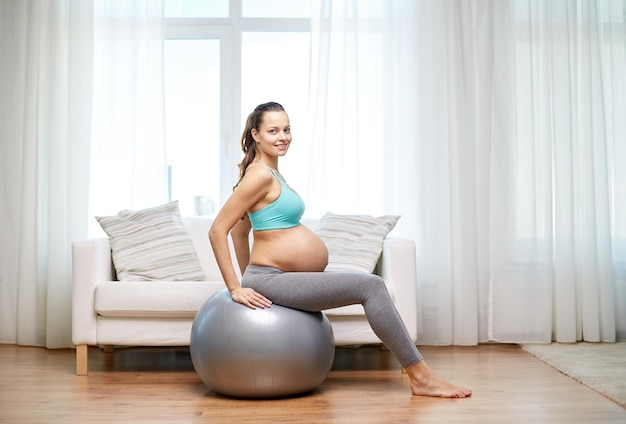 concept de grossesse, de sport, de fitness, de personnes et de mode de vie sain - femme enceinte heureuse faisant de l'exercice à la maison