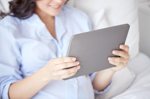 Concept de grossesse, de technologie, de personnes et d'attente - gros plan de femme enceinte avec ordinateur tablette pc au lit à la maison