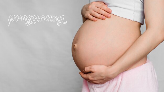 Concept de grossesse. Ventre d'une fille enceinte avec les mains