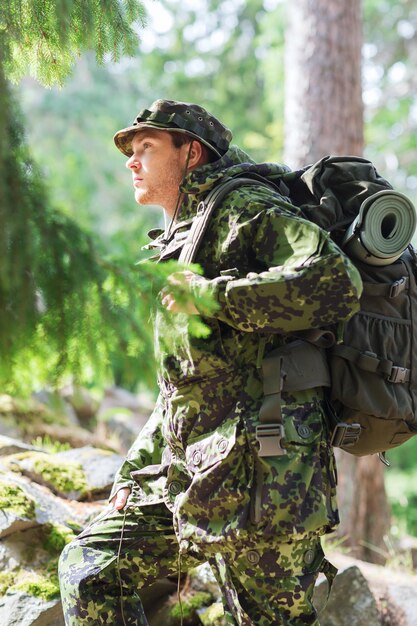 concept de guerre, de randonnée, d'armée et de personnes - jeune soldat ou ranger avec sac à dos marchant dans la forêt