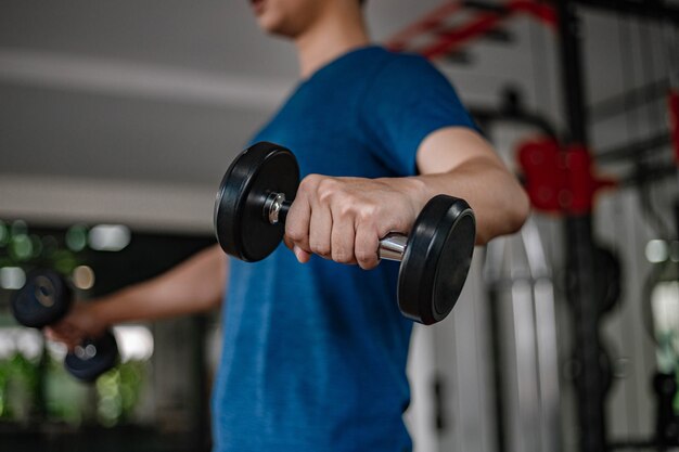 Concept de gym d'entraînement un jeune adulte utilisant son bras musclé et puissant soulevant un haltère vers le haut et vers le bas dans la salle de gym.