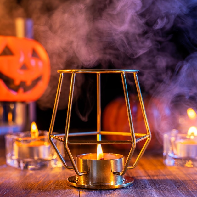 Concept d'Halloween décorations fantasmagoriques avec bougie allumée et porte-bougie avec fumée de ton bleu autour d'une table en bois sombre gros plan