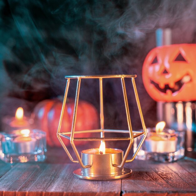 Concept d'Halloween décorations fantasmagoriques avec bougie allumée et porte-bougie avec fumée de ton vert autour d'une table en bois sombre gros plan