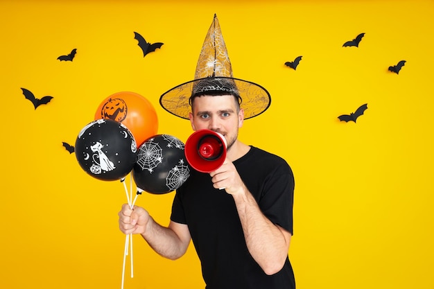 Concept d'Halloween Guy avec des ballons d'Halloween et un mégaphone sur fond jaune