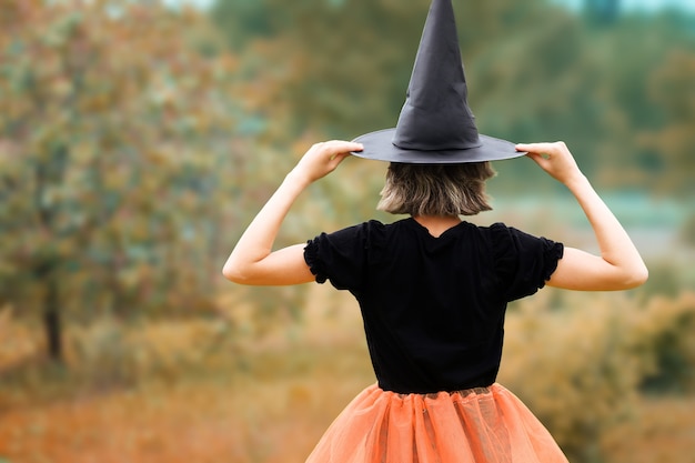 Concept d'Halloween jeune sorcière au chapeau noir debout en arrière