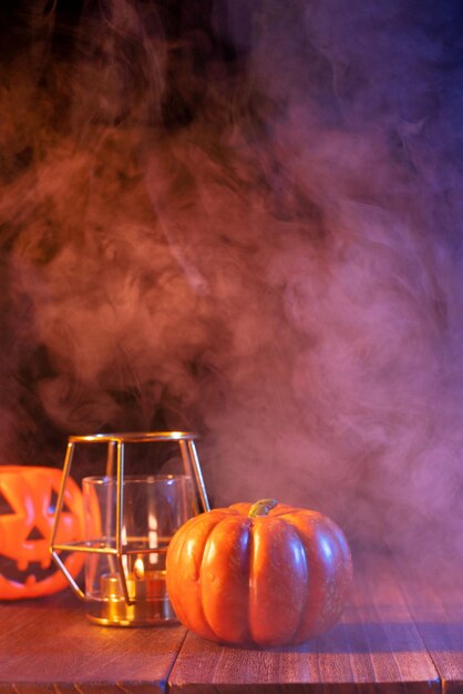 Concept d'Halloween lanterne de citrouille orange et bougies sur une table en bois sombre avec de la fumée bleue orange autour de l'arrière-plan truc ou friandise en gros plan