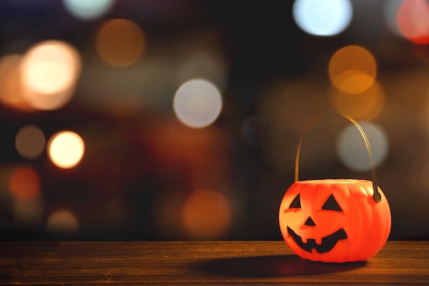 Concept d'Halloween - Lanterne citrouille en plastique orange sur une table en bois sombre avec une lumière scintillante floue en arrière-plan, trick or Treat, Close up