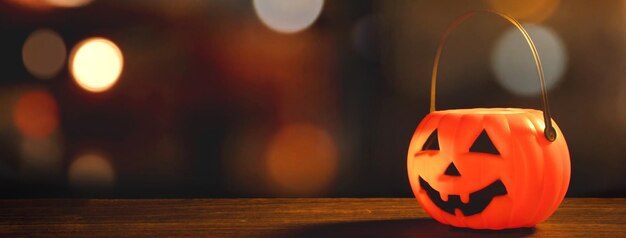 Concept d'Halloween Lanterne citrouille en plastique orange sur une table en bois sombre avec une lumière scintillante floue en arrière-plan trick or treat close up