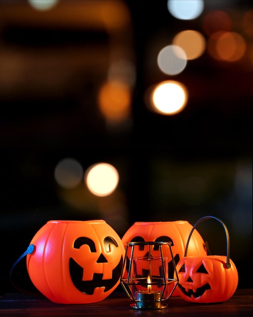 Concept d'Halloween Lanterne citrouille en plastique orange sur une table en bois sombre avec une lumière scintillante floue en arrière-plan trick or treat close up