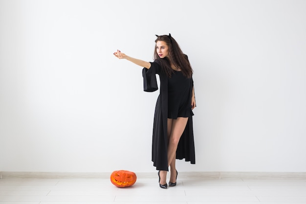 Concept d'Halloween et de mascarade - Belle jeune femme posant avec citrouille Jack-o'-lantern sur fond clair avec espace de copie