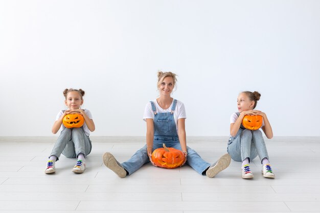 Concept d'halloween et de vacances heureux - Une mère et ses filles avec des citrouilles. Héhé, préparation pour Halloween.