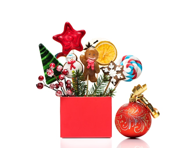 Concept d'hiver avec des décorations du nouvel an et des bonbons isolés sur fond blanc. Carte de fête de Noël avec du pain d'épice de Noël et des bonbons sur des bâtons dans une boîte-cadeau.