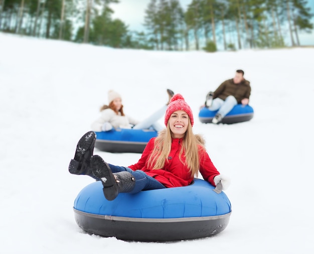 concept d'hiver, de loisirs, de sport, d'amitié et de personnes - groupe d'amis heureux glissant sur des tubes à neige