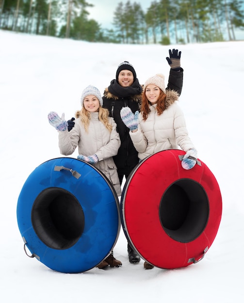 concept d'hiver, de loisirs, de sport, d'amitié et de personnes - groupe d'amis souriants avec des tubes à neige agitant les mains à l'extérieur