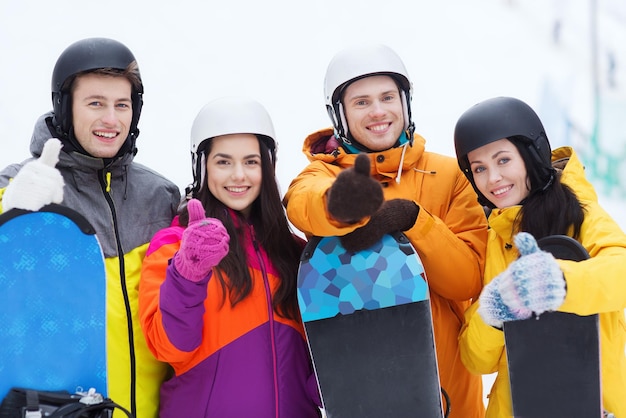 concept d'hiver, de loisirs, de sport extrême, d'amitié et de personnes - amis heureux dans des casques avec des planches à neige