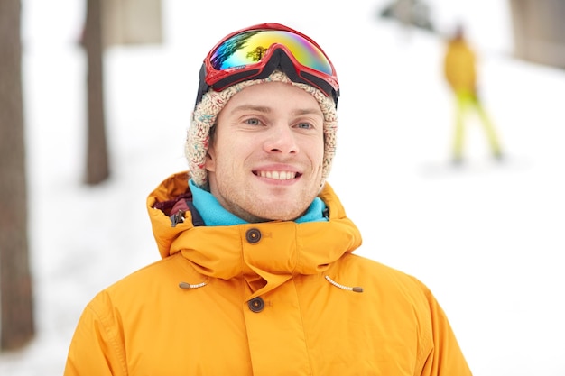 Photo concept d'hiver, de loisirs, de sport et de personnes - jeune homme heureux en lunettes de ski à l'extérieur