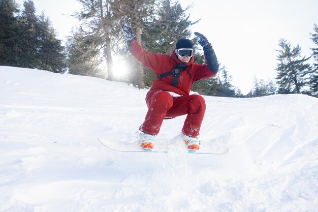 Concept d'hiver, de loisirs, de sport et de personnes - Snowboarder actif sautant dans les montagnes par une journée ensoleillée. Planche à neige agrandi. Station de ski de Sheregesh