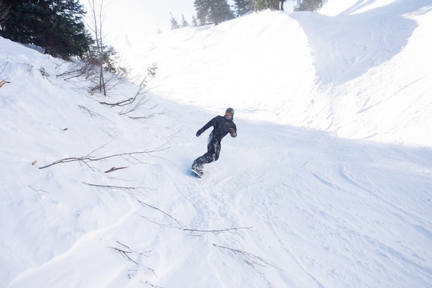 Concept d'hiver, de loisirs, de sport et de personnes - Snowboarder actif sautant dans les montagnes par une journée ensoleillée. Planche à neige agrandi. Station de ski de Sheregesh