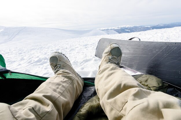 Concept d'hiver, de loisirs, de sport et de personnes - Snowboarder se trouve dans une tente. l'amour du pic de l'alpiniste garçon, l'amour du camp et de la montagne