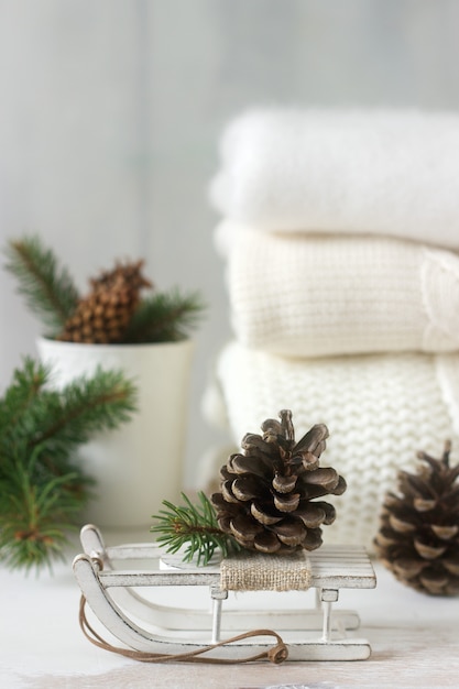 Concept d'hiver avec pull couverture blanche, gants, traîneaux, tasse, cônes et branches de sapin.
