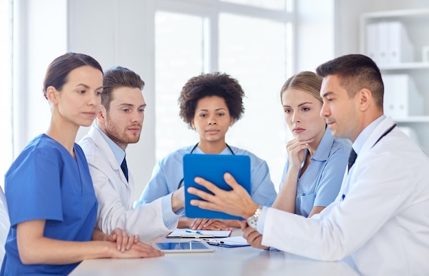 concept d'hôpital, de profession, de personnes et de médecine - groupe de médecins heureux avec des ordinateurs tablettes se réunissant au cabinet médical