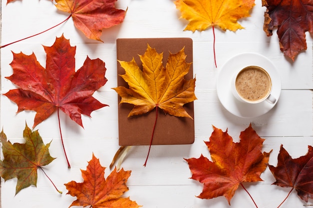 Le concept de l&#39;humeur d&#39;automne. Café du matin, agenda et feuilles d&#39;érable colorées.