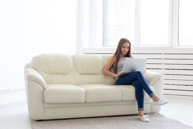 Concept d'indépendant et de personnes - Jeune femme assise sur un canapé et travaillant sur un ordinateur portable.