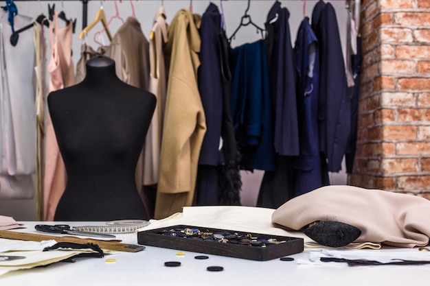 Photo concept d'intérieur de studio de design créatif de mode avec mannequin mannequin et vêtements à la mode élégants à la mode sur des cintres, lieu de travail de couture, atelier de couture, atelier de couture