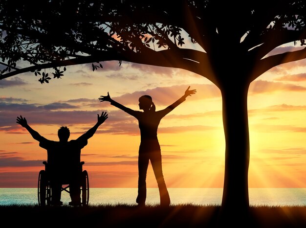 Concept d'invalidité et de maladie. Silhouette heureuse handicapée et gardienne sous un arbre au coucher du soleil