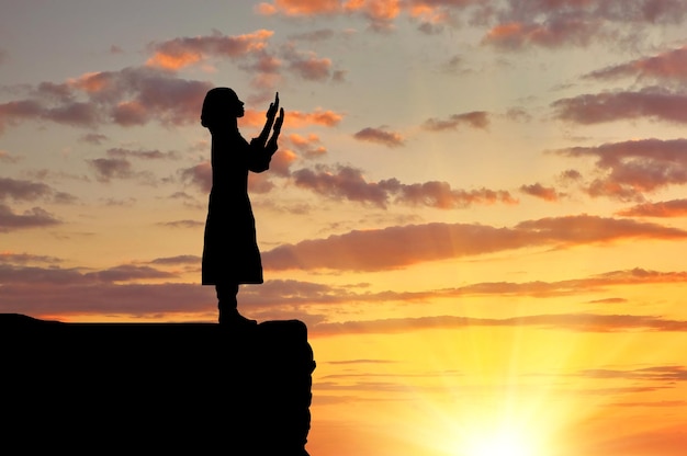 Le concept de l'Islam est la religion. Silhouette de femme en prière sur une colline au coucher du soleil