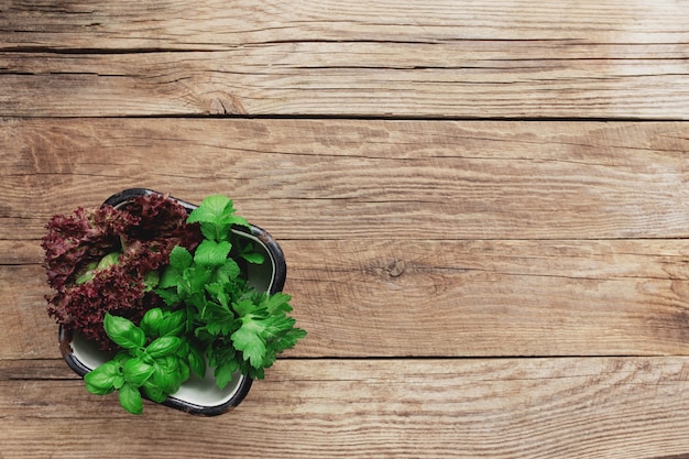 Concept de jardinage et d'alimentation saine avec différentes herbes et feuilles de salade sur fond de bois dans un récipient en métal blanc