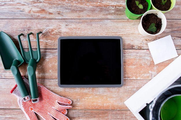 concept de jardinage, de technologie et de plantation - gros plan sur un écran vierge d'ordinateur tablette, des semis, des graines et des outils de jardin sur la table