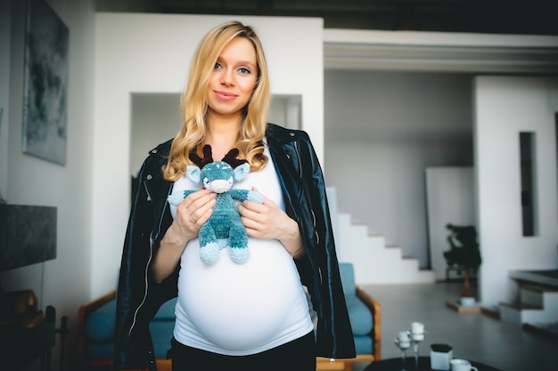 Concept Jeune belle fille blonde caucasienne enceinte souriante heureuse debout dans le salon