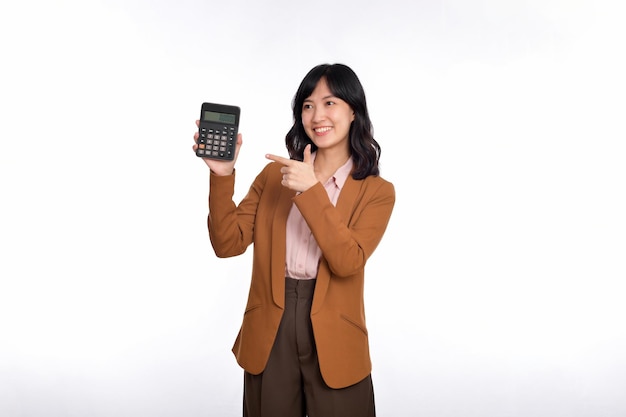 Concept de jour d'impôt Femme asiatique confiante souriante tenant la calculatrice et l'appareil de pointage du doigt Portrait heureuse femme asiatique isolée sur fond blanc Compte et finances comptant le revenu