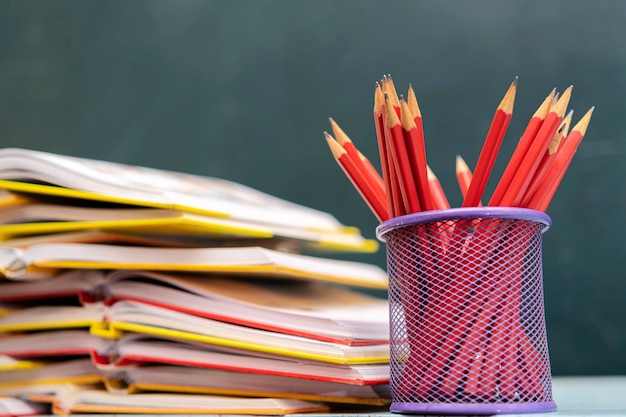 Concept à la journée des enseignants Stylos crayons livres sur table sur fond de tableau Retour à l'école