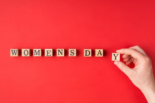 Concept de la journée de la femme heureuse. Vue rapprochée photo de mains féminines faisant une phrase mettant un bloc de bois dans une ligne isolée sur fond de couleur vive