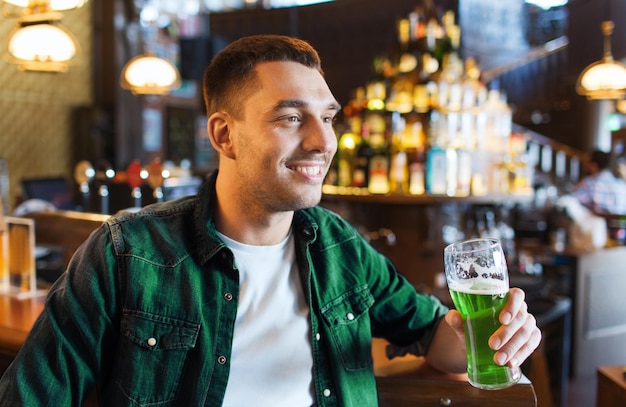 Le concept de la journée de Saint-Patrick est celui d'un jeune homme heureux buvant de la bière verte dans un bar ou un pub.