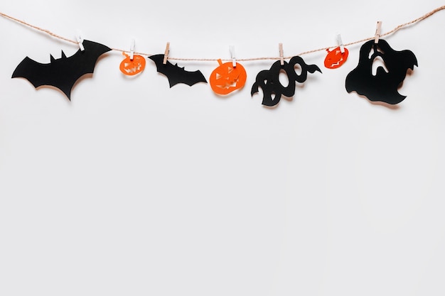 Concept de joyeuses fêtes d'halloween. Chauves-souris, citrouilles et fantômes sur corde avec pince à linge sur fond isolé blanc