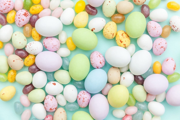 Concept de joyeuses Pâques. Bonbons de Pâques oeufs en chocolat et bonbons jellybean isolés sur fond bleu pastel à la mode