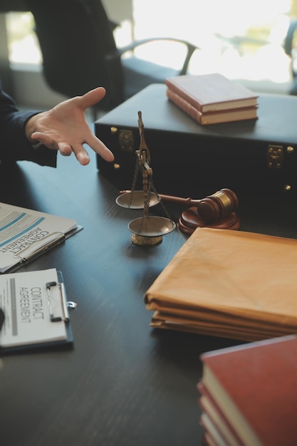 Photo concept de justice et de droit le conseiller juridique présente au client un contrat signé avec un marteau et le droit juridique ou juridique ayant une réunion d'équipe dans un cabinet d'avocats en arrière-plan