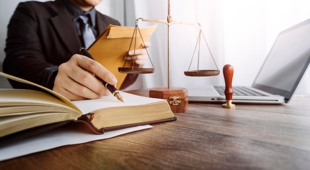 Concept de justice et de droitJuge masculin dans une salle d'audience avec le marteau travaillant avec un ordinateur et des lunettes de clavier d'amarrage sur la table à la lumière du matin