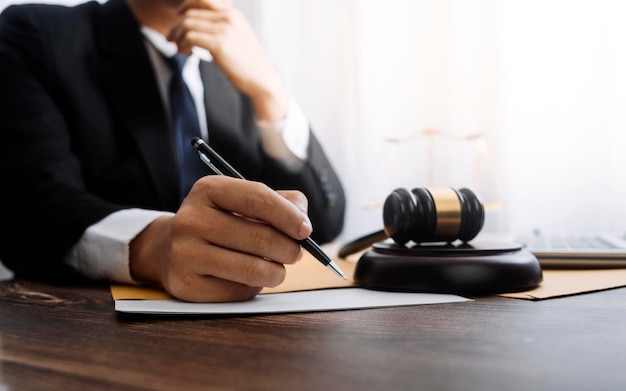 Concept de justice et de droitJuge masculin dans une salle d'audience avec le marteau travaillant avec un ordinateur et des lunettes de clavier d'amarrage sur la table à la lumière du matin