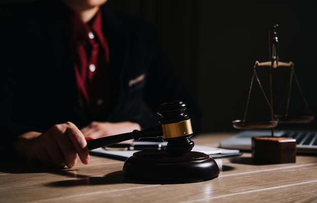 Concept de justice et de droitJuge masculin dans une salle d'audience avec le marteau travaillant avec un ordinateur et des lunettes de clavier d'amarrage sur la table à la lumière du matin