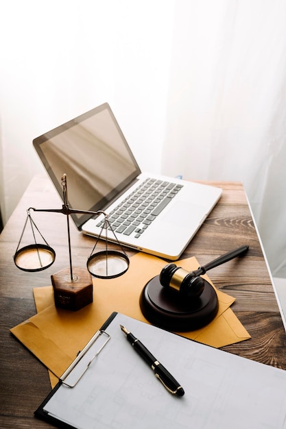 Photo concept de justice et de droitjuge masculin dans une salle d'audience avec le marteau travaillant avec un ordinateur et des lunettes de clavier d'amarrage sur la table à la lumière du matin