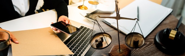 Photo concept de justice et de droitjuge masculin dans une salle d'audience avec le marteau travaillant avec un ordinateur et des lunettes de clavier d'amarrage sur la table à la lumière du matin