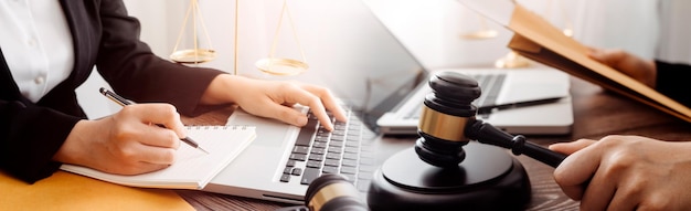 Concept de justice et de droitJuge masculin dans une salle d'audience avec le marteau travaillant avec un ordinateur et des lunettes de clavier d'amarrage sur la table à la lumière du matin