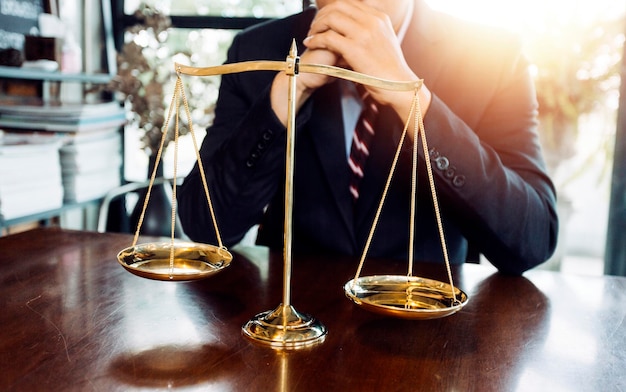 Concept de justice et de droitJuge masculin dans une salle d'audience avec le marteau travaillant avec un ordinateur et des lunettes de clavier d'amarrage sur la table à la lumière du matin