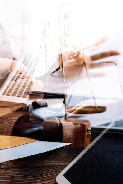 Photo concept de justice et de droitjuge masculin dans une salle d'audience avec le marteau travaillant avec un ordinateur et des lunettes de clavier d'amarrage sur la table à la lumière du matin