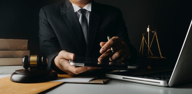 Concept de justice et de droitJuge masculin dans une salle d'audience avec le marteau travaillant avec un ordinateur et des lunettes de clavier d'amarrage sur la table à la lumière du matin